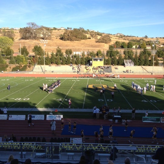 This photo shows Oak Ridge High School's football field with players on the field, hills in the background and bleachers in the foreground.