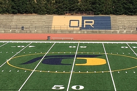 This photo shows Oak Ridge High School's football field on the 50 yard line with bleachers in the background.